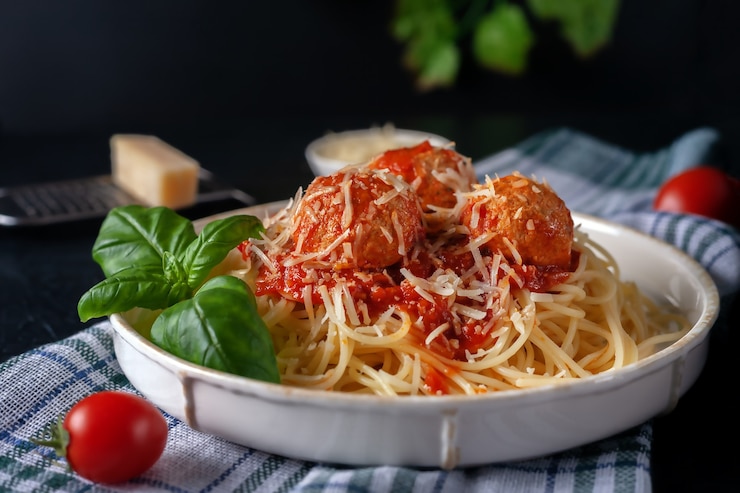 Foto deliziosi spaghetti con polpette, parmigiano e salsa di pomodoro su un piatto sopra un panno da cucina