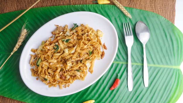 Deliziosi spaghetti di riso fritti o char kway teow o kwetiau con uova e verdure Cibo di strada indonesiano