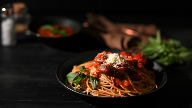 Deliziosi spaghetti serviti su un piatto nero con sfondo scuro da pranzo Immagine del primo piano del cibo italiano