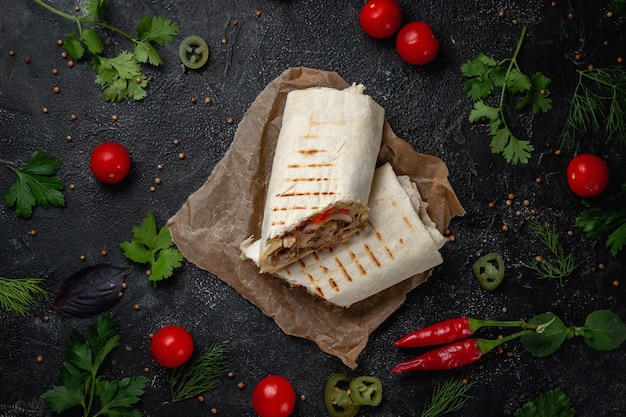 Deliziosi tacos di shawarma e lavash su un tavolo di pietra scura. Ristorante fast food. Opzione salutare di fast food. Gustosi panini freschi con carne di manzo e verdure, spuntino tradizionale mediorientale