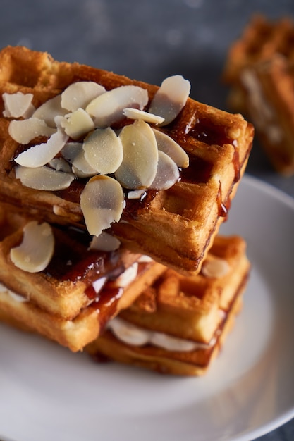 Deliziosi waffle fatti in casa di Vienna con sciroppo e mandorle briciole serviti su un tavolo grigio