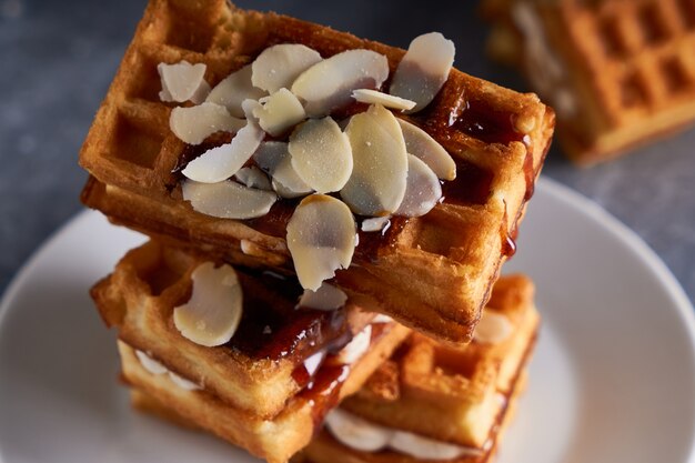 Deliziosi waffle fatti in casa di Vienna con sciroppo e mandorle briciole serviti su un tavolo grigio