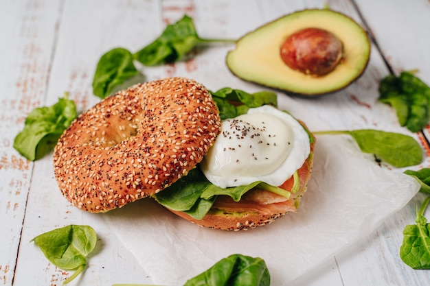 Delizioso bagel con pane al sesamo e chia, al suo interno contiene salmone, uovo fritto e basilico.