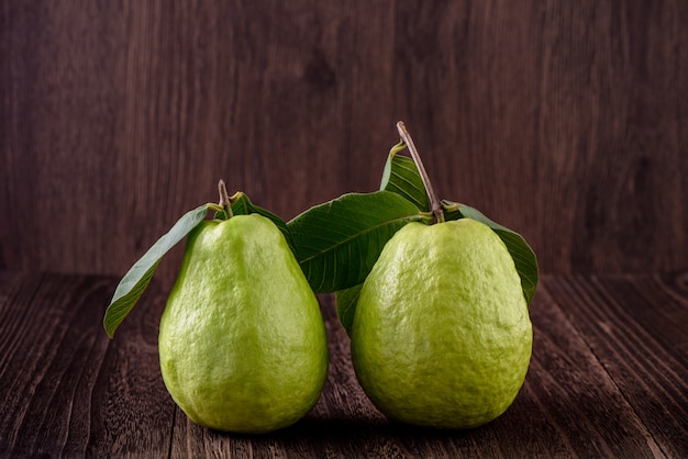 Delizioso bellissimo set Guava con foglie fresche isolato su sfondo tavolo in legno, primi piani.