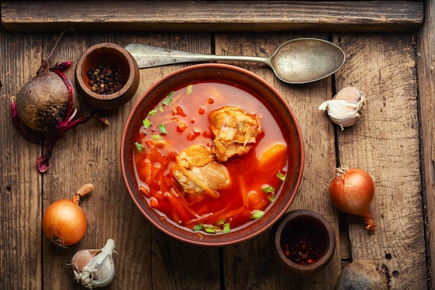 Delizioso borscht rosso ucraino in un piatto su un vecchio tavolo di legno rustico