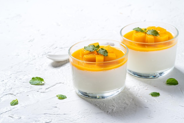 Delizioso budino di mousse di panna cotta al mango doppio colorato su sfondo bianco della tavola