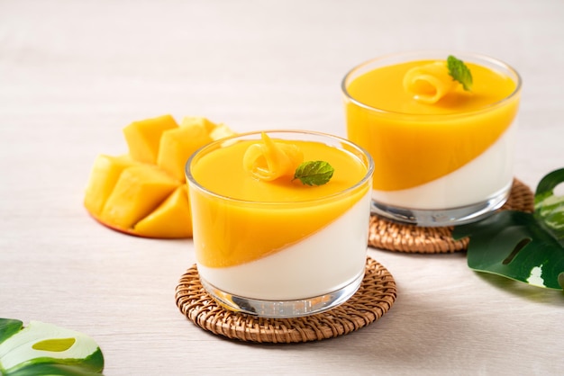 Delizioso budino di mousse di panna cotta al mango doppio colorato su sfondo di tavolo in legno