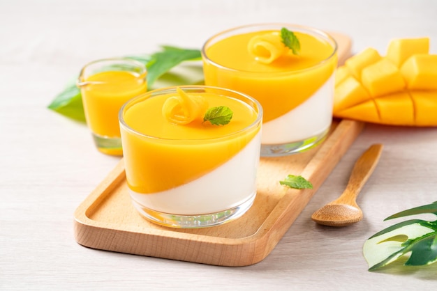 Delizioso budino di mousse di panna cotta al mango doppio colorato su sfondo di tavolo in legno