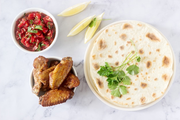 Delizioso cibo fatto in casa con tortillas, salsa e ali fritte.