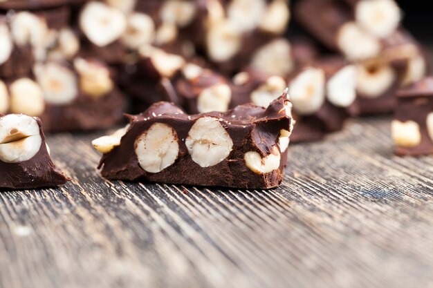 Delizioso cioccolato artigianale al latte con tante nocciole, noci e prodotti naturali del cacao nella produzione del cioccolato con nocciole