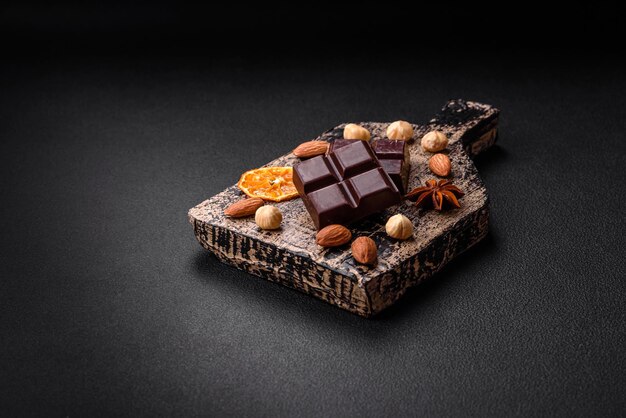Delizioso cioccolato nero dolce rotto in cubetti su un tagliere di legno