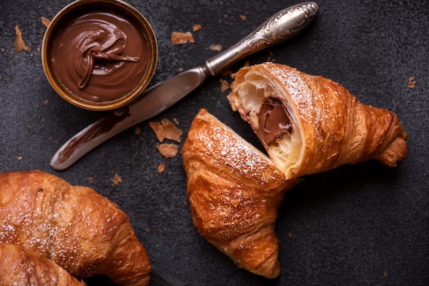 Delizioso croissant dolce con cioccolato su sfondo scuro