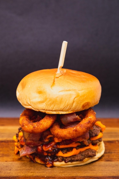 Delizioso doppio hamburger di manzo cheddar con pancetta e anelli di cipolla fritti