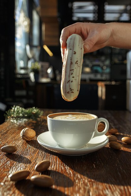 delizioso eclair in piedi al tavolo con una tazza di caffè squisito nella caffetteria