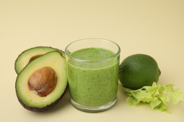 Delizioso frullato verde in vetro e prodotti su sfondo beige in primo piano