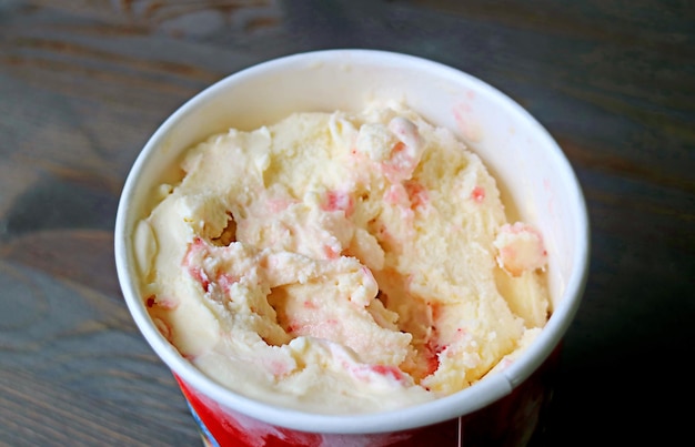 Delizioso gelato alla fragola e banana in una tazza grande sul tavolo di legno nero