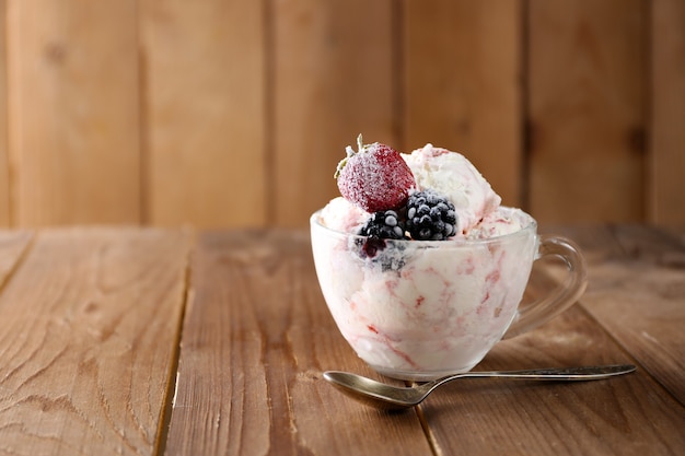 Delizioso gelato con frutti di bosco freschi congelati, su fondo di legno rustico