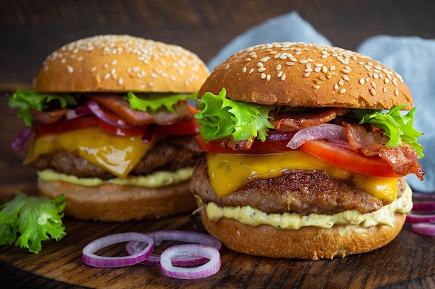 Delizioso hamburger di manzo con fetta di pancetta, formaggio, lattuga e pomodoro. Hamburger da fast food gustoso