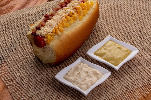 Delizioso hot dog con ingredienti e su sfondo colorato o in legno