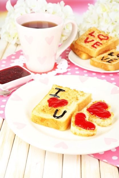 Delizioso pane tostato con marmellata e tazza di tè sul primo piano del tavolo