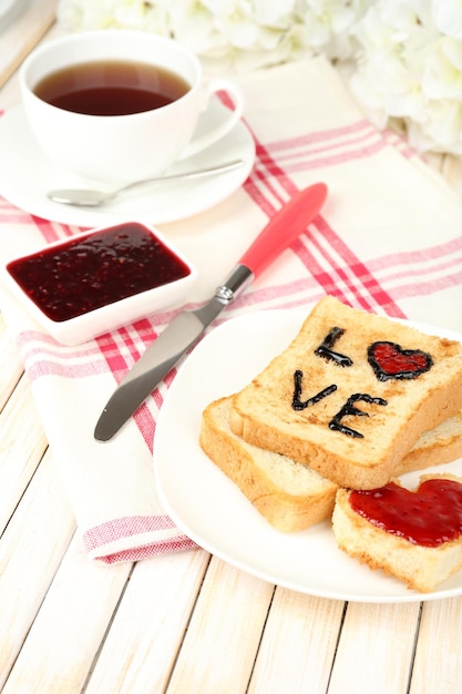 Delizioso pane tostato con marmellata e tazza di tè sul primo piano del tavolo