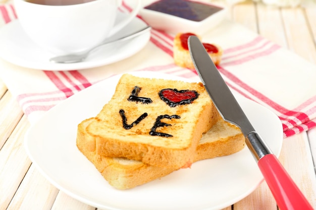 Delizioso pane tostato con marmellata e tazza di tè sul primo piano del tavolo