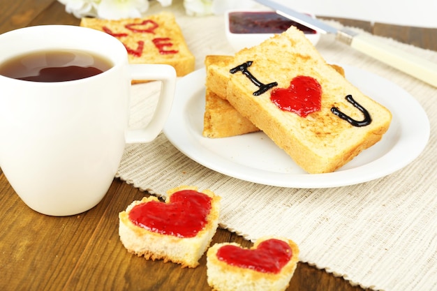 Delizioso pane tostato con marmellata e tazza di tè sul primo piano del tavolo