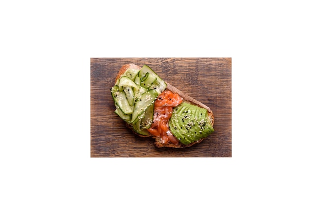 Delizioso pane tostato integrale con cetriolo avocado salmone e semi di sesamo su uno sfondo di cemento strutturato