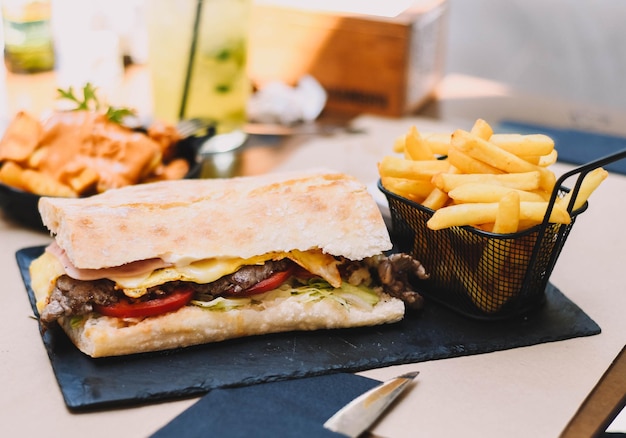 Delizioso panino con filetto di manzo con prosciutto e formaggio accompagnato da patatine fritte