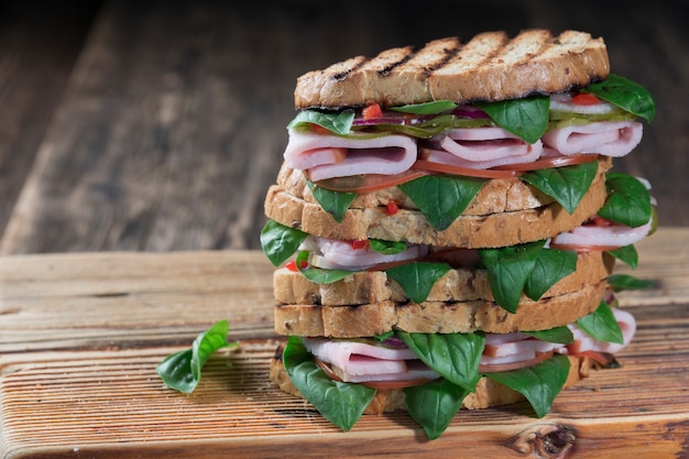 Delizioso panino con prosciutto ed erbe aromatiche ravvicinate su un tagliere