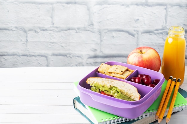 Delizioso panino sano in una scatola per il pranzo, biscotti e ciliegie. Porta il pranzo con te a scuola o in ufficio. Succo in una bottiglia e una mela.