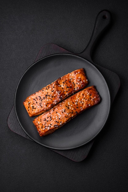 Delizioso pesce rosso alla griglia fresco con sale spezie ed erbe aromatiche su uno sfondo di cemento scuro