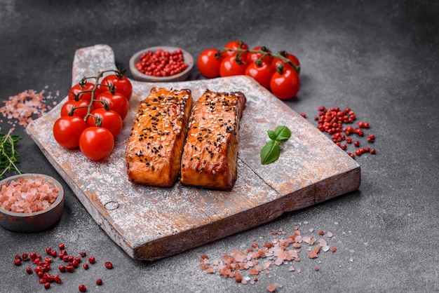 Delizioso pesce rosso alla griglia fresco con sale spezie ed erbe aromatiche su uno sfondo di cemento scuro