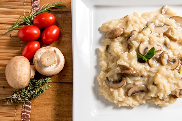 Delizioso piatto di risotto ai funghi pomodorini ed erbe aromatiche si chiuda