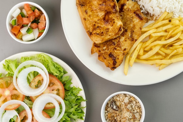 Delizioso piatto esecutivo di filetto di pollo, riso, fagioli, patatine fritte e insalata verde con lattuga, pomodoro e cipolla accompagnati da farofa e vinaigrette Tipico cibo brasiliano Focus selettivo