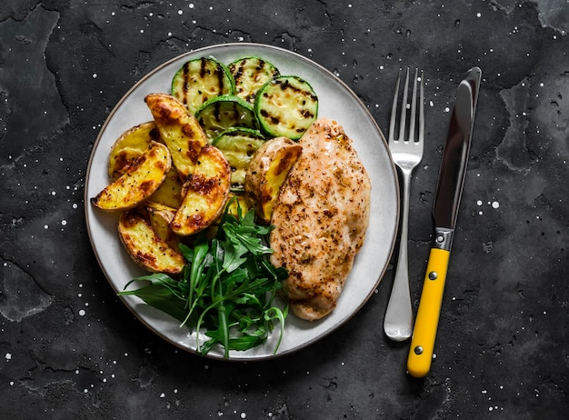 Delizioso pranzo patate al forno petto di pollo zucchine grigliate e insalata di spinaci rucola