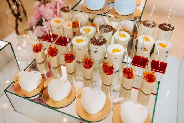Delizioso ricevimento di nozze bar di caramelle tavolo di dessert pieno di torte e dolci e fiori fiori di ciliegio cinese sullo sfondo di un ristorante squisito