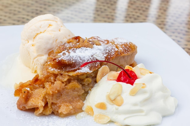 Delizioso strudel di mele, pallina di gelato alla vaniglia e panna montata con mandorle e ciliegie