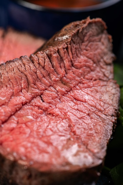 Delizioso Succoso pezzo di bistecca alla griglia con spinaci e salse su un piatto blu lucido Bistecca a fette Medio al sangue Un pranzo gourmet abbondante Ristorazione