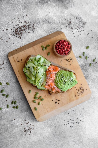 Delizioso toast di pane integrale con cetriolo avocado salmone e semi di sesamo