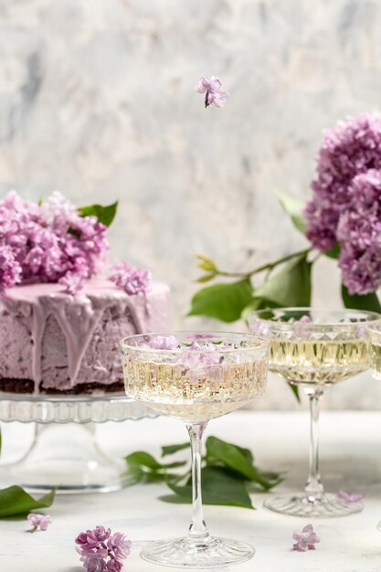 Delizioso vino champagne prosecco con torta di mousse ai frutti di bosco bouquet di lillà in fiore viola Cucina francese sfondo da cartolina