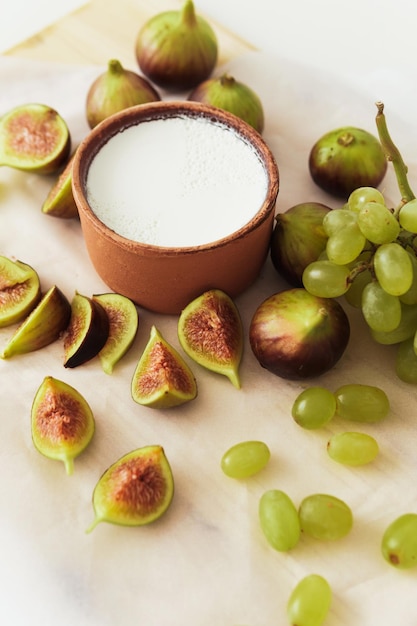 Delizioso yogurt greco naturale in ciotola di argilla con fichi e uva