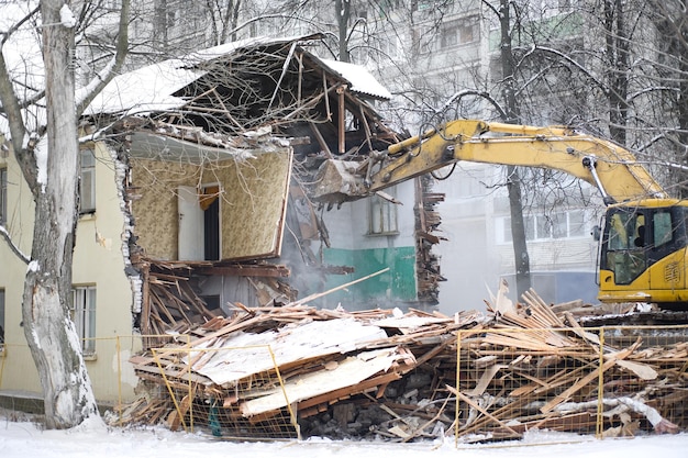 Demolizione di edifici L'escavatore rompe la vecchia casa a due piani Paesaggio urbano industriale con processo di distruzione