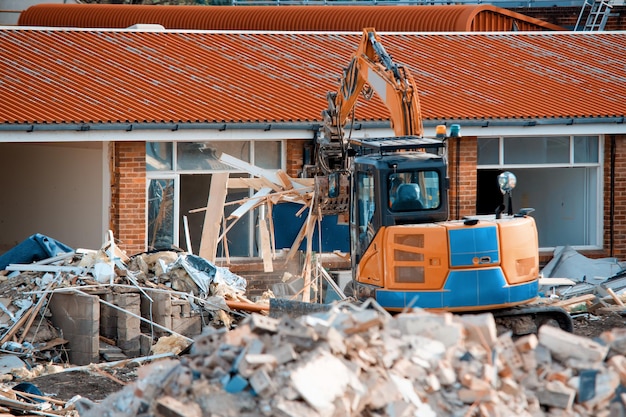 Demolizione di edifici L'escavatore rompe la vecchia casa Fare spazio per la costruzione di nuove case