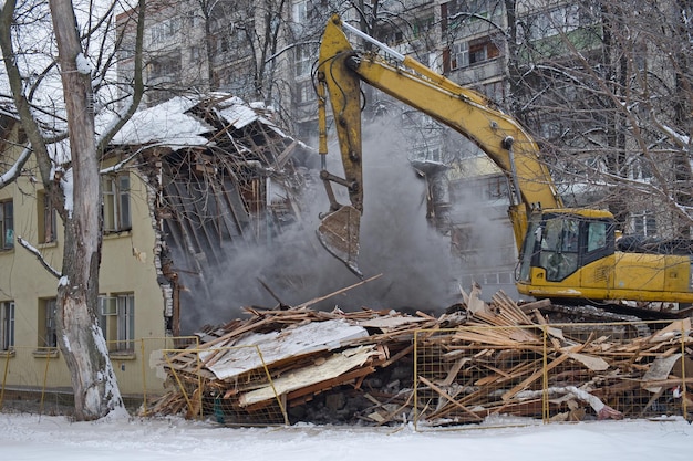 Demolizione di edifici L'escavatore rompe la vecchia casa Paesaggio urbano industriale con processo di distruzione