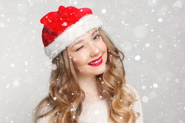 Dentale, natale, natale, inverno, concetto di felicità - donna sorridente con cappello da Babbo Natale, bellissimo modello femminile indossa cappello da Babbo Natale. ragazza con l'apparecchio, odontoiatria