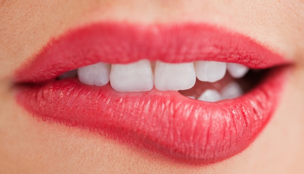 Denti bianchi di una donna che si morde le labbra
