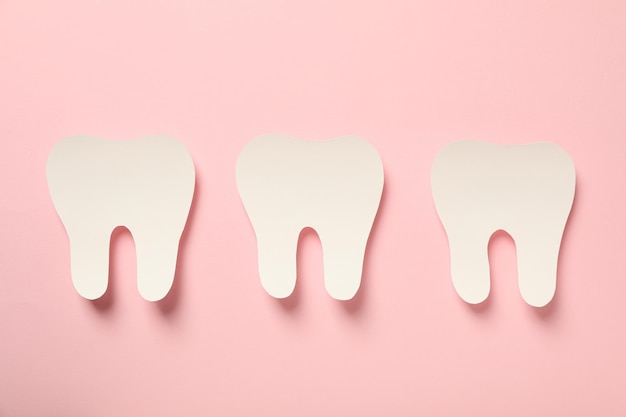 Denti con strumenti dentali per la cura su uno sfondo rosa