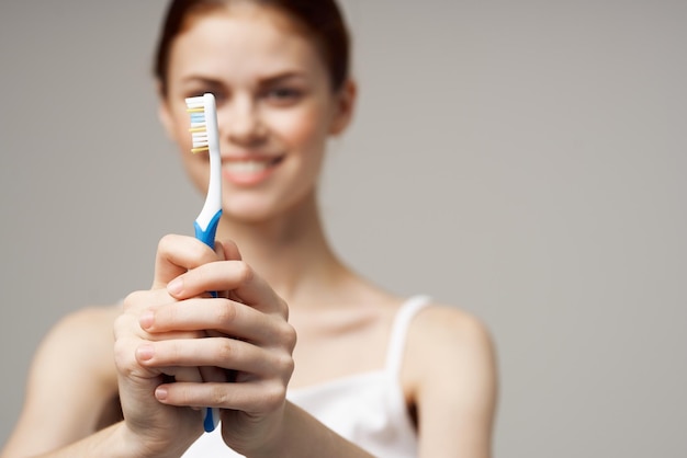 Dentifricio in pasta della donna graziosa che lava i denti salute dentale sfondo chiaro