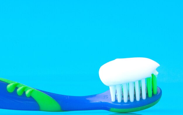 Dentifricio su uno spazzolino da denti su sfondo blu